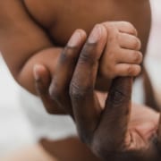 Newborn child holding parents hand