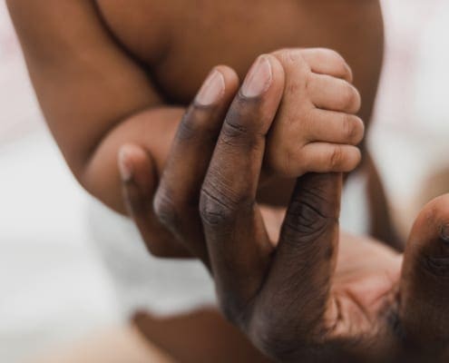 Newborn child holding parents hand